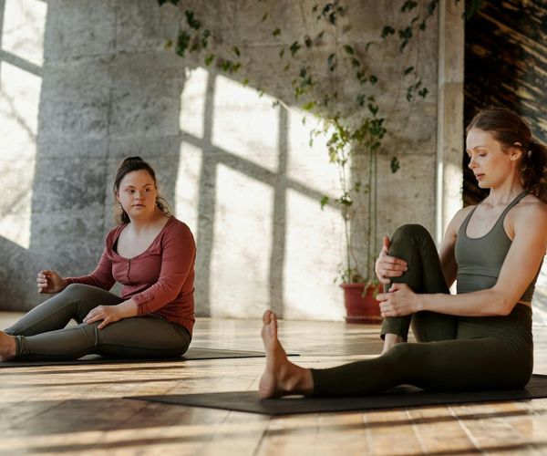 Person stretching gently on a yoga mat in a sunlit room.